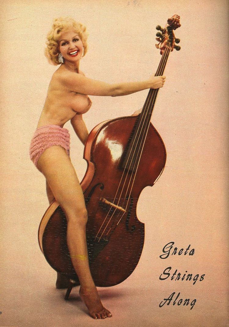 Greta Thyssen holding the cello while wearing pink sexy short