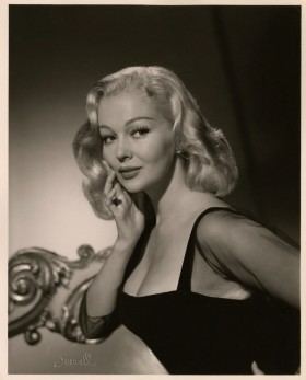 Greta Thyssen in her curly hair and wearing black sexy dress while hand on her face