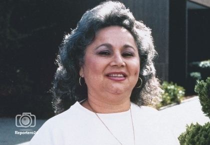 Griselda Blanco smiling while wearing a white blouse, necklace, and earrings