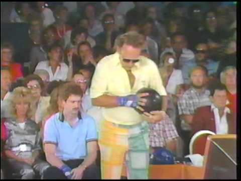 Guppy Troup standing and holding a bowling ball while wearing a yellow shirt in PBA Pro Bowlers Tour