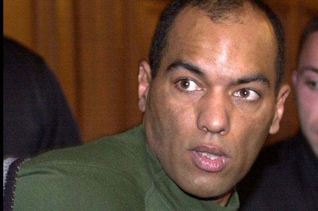 Guy Georges looking at something during his trial while wearing a green t-shirt