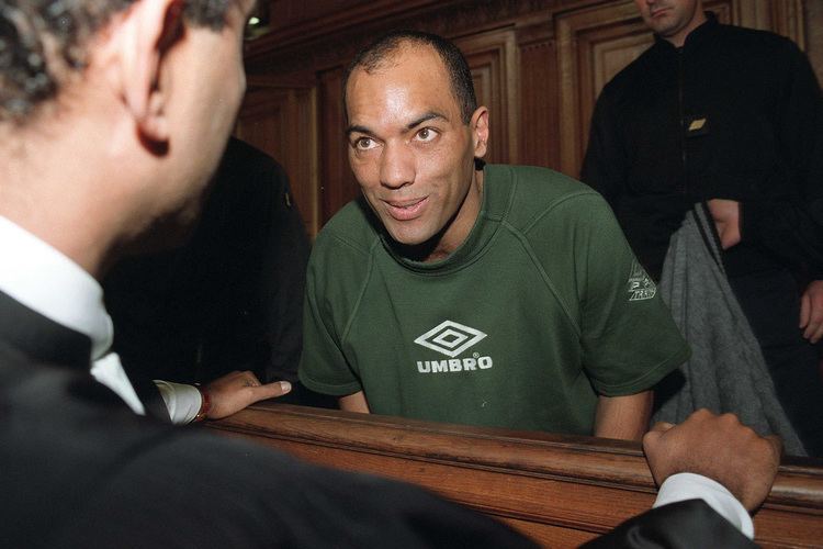 Guy Georges talking with one of his lawyers during the trial while wearing a green t-shirt