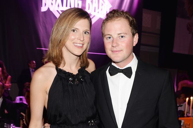 Guy Pelly smiling and wearing a black coat, white long sleeves, and bow tie while Lizzy Wilson wearing a black sleeveless dress