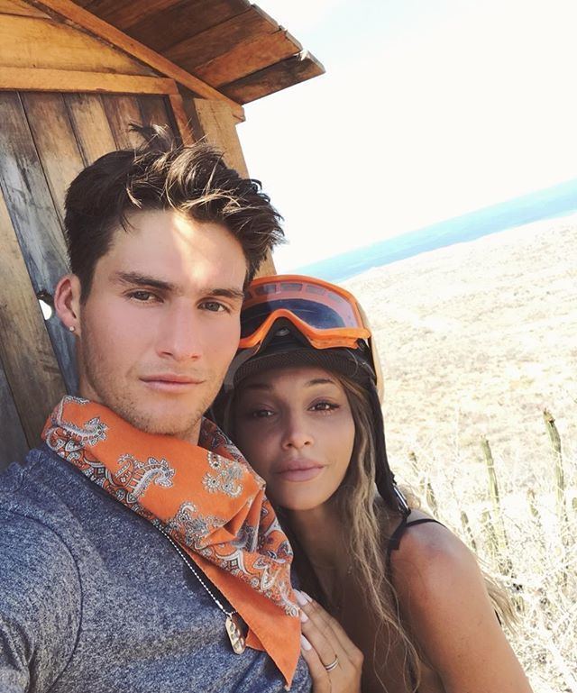 Haley Giraldo smiling and wearing a black tank top and headgear while leaning into his boyfriend, Matt Wiliam, wearing  a gray shirt and scarf