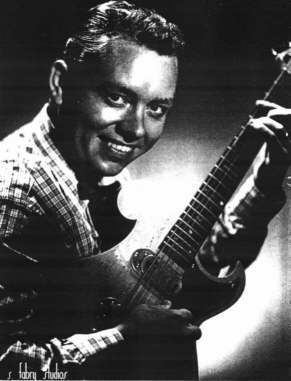 A young Hank Garland smiling while playing a guitar.