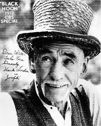 Hank Worden smiling while wearing a hat, vest and long sleeves