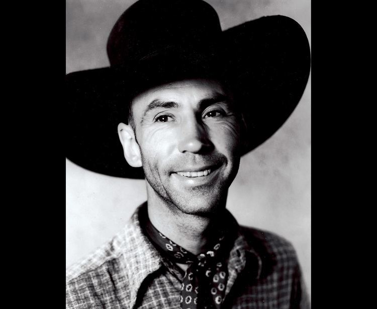 Hank Worden smiling while wearing a hat and checkered long sleeves