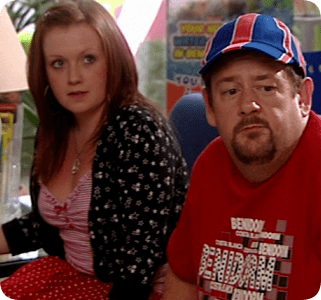 Hannah Hobley wearing a black floral blazer and white and red striped blouse while Johnny Vegas wearing a red t-shirt and red and blue cap