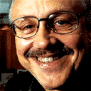 Hans Snook smiling, with a mustache, wearing eyeglasses and a black shirt.