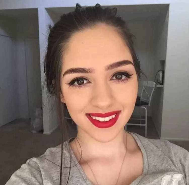 Hariel Ferrari smiling with hair tied, thick eyelashes, and wearing a gray blouse and silver necklace