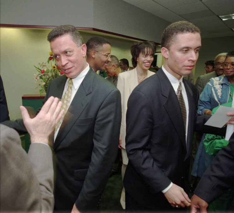 Harold Eugene Ford Sr. and Harold Eugene Ford Jr. wearing suits with a group of people.
