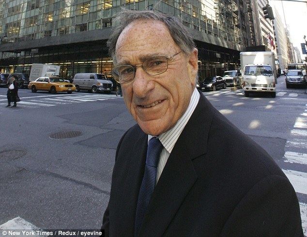 Harry B. Macklowe smiling while wearing eyeglasses, black coat, striped long sleeves, and blue necktie