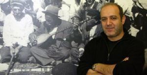 Hasan Saltık in front of a picture of a group of men