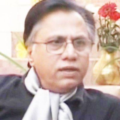 Hassan Nisar wearing eyeglasses, a black shirt, and a scarf.