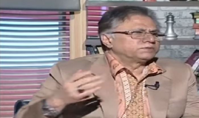 Hassan Nisar during an interview while wearing eyeglasses and a brown coat.