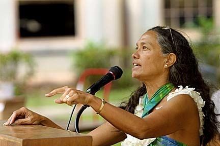 Haunani-Kay Trask giving a speech while wearing white and green dress