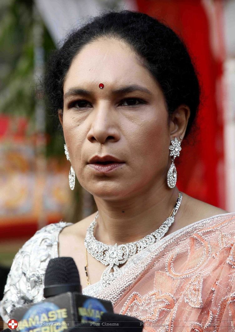 Heeba Shah talking into a microphone while wearing earrings, a necklace, and a formal dress