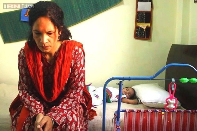 Heeba Shah sitting on the bed with a baby lying down