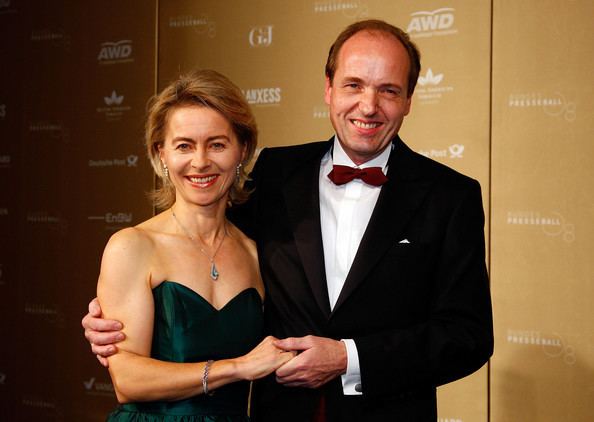 Heiko von der Leyen smiling and wearing black coat and white long sleeves while Ursula von der Leyen wearing a dark green dress