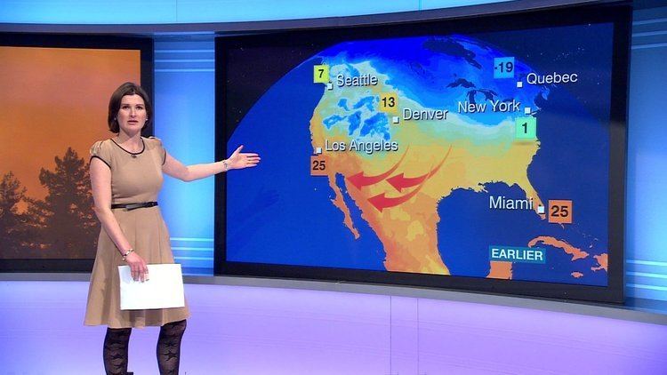 Helen Willetts at work as a meteorologist while wearing black and brown dress