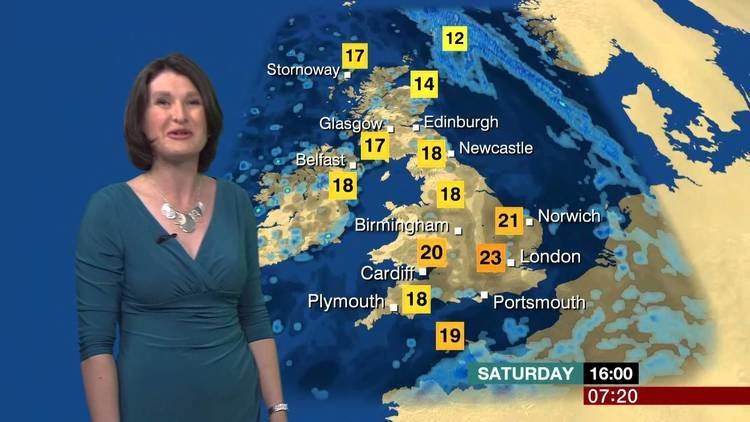 Helen Willetts at work as a meteorologist while wearing blue dress