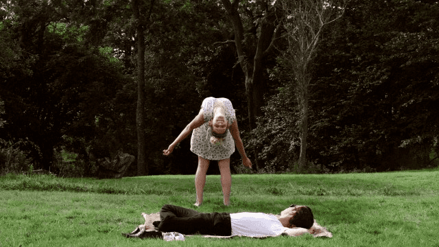 Josh O'Connor lying on the grass while Hannah Arterton looking at him in a scene from the 2014 romantic drama film, Hide and Seek