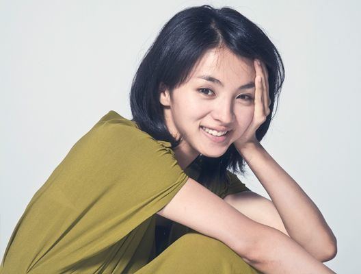 Hikari Mitsushima is smiling, has black hair, left hand on her face, wearing a green dress.