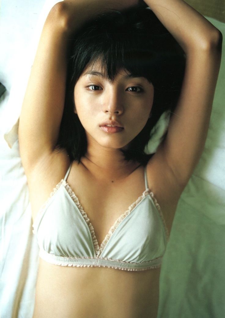 Hikari Mitsushima is serious, has black hair, both hands up, a mole on her chest, laying down on a white cloth, and wearing white lingerie.