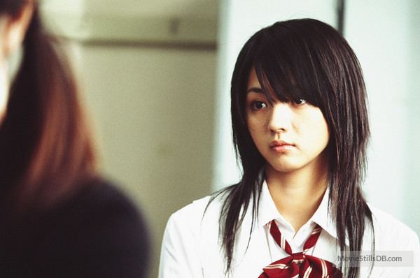 In front is a woman, has brown hair wearing a black shirt, behind is Hikari Mitsushima is serious, has black hair, wearing a white polo with a red and white necktie.