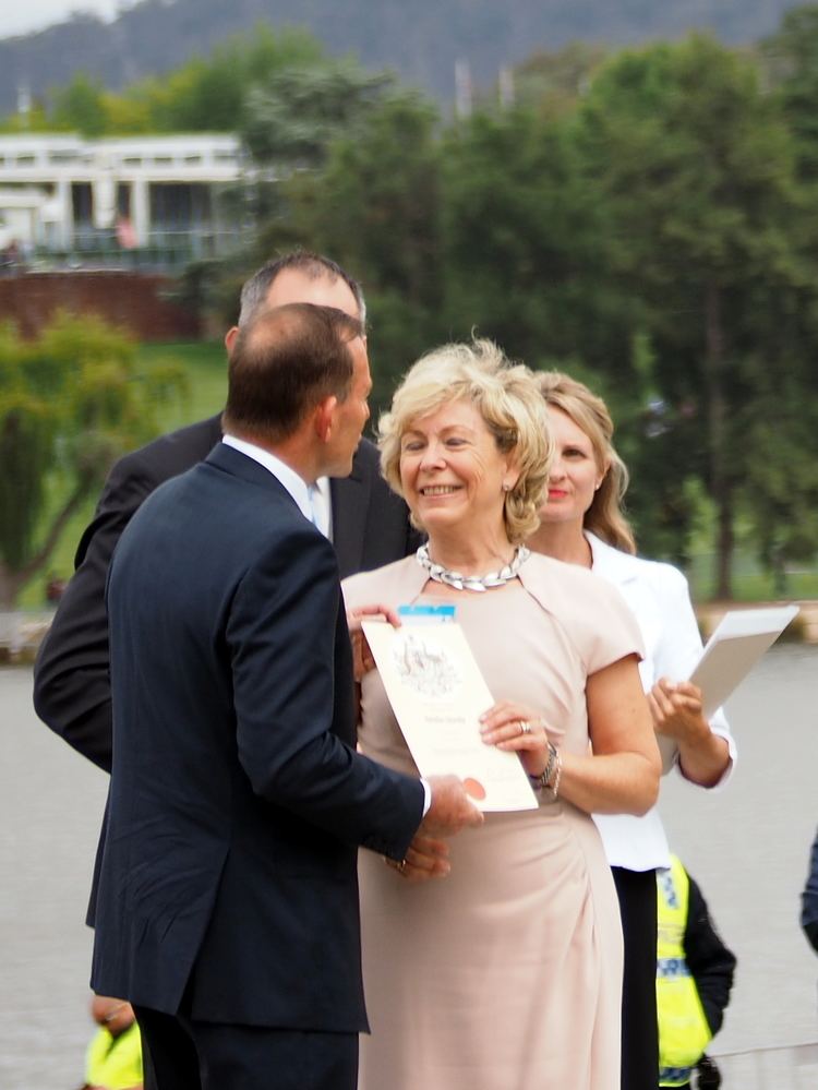 Hilary Kay smiling while receiving her certificate of Australian citizenship from Tony Abbott