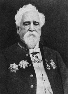 Hiram Maxim wearing a shirt and a coat with some attached badges (a black and white photo)