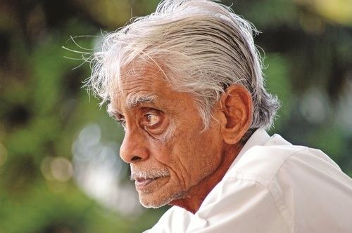 Hiren Bhattacharyya with his white hair wearing a white collared shirt outside