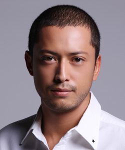 Hiroyuki Ikeuchi with a serious face and wearing white long sleeves.