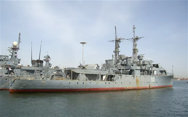 HMS Whimbrel (U29) docked at a port in a dusk hour along with other ships.