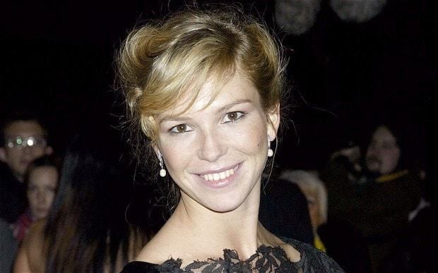 Honeysuckle smiling with blonde hair and wearing a black lace dress and dangling earrings