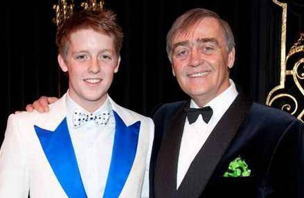 Hugh Grosvenor smiling and posing with his father Gerald Grosvenor while wearing a white and blue formal attire.