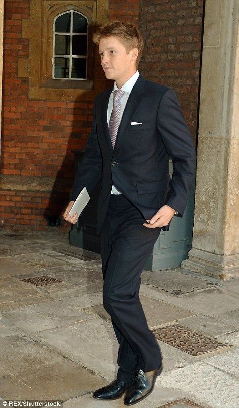 Hugh Grosvenor walking and holding a sheet of paper while wearing a black formal attire with a gray tie.