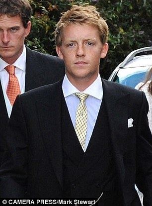 Hugh Grosvenor walking while wearing a black suit and a sky blue long sleeve with a yellow tie.