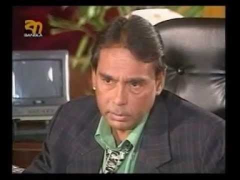 Humayun Faridi wearing black coat and green long sleeves while sitting on the chair