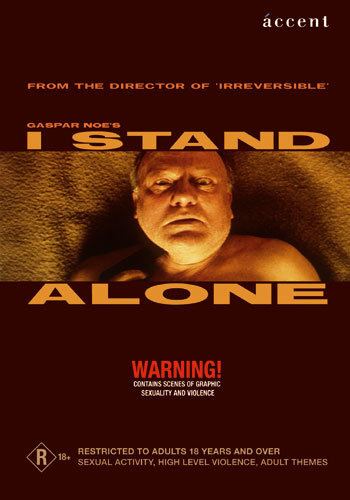 A clip from the 1998 movie “I Stand Alone”, with a phrase above “from the director of irreversible gaspar Noe’s I stand”, and a phrase below, “Alone, warning! Contains scenes of graphic sexuality and violence”. Philippe Nahon seriously looking and laying on a brown color blanket while holding a gun pointing at his neck, he had gray hair and topless