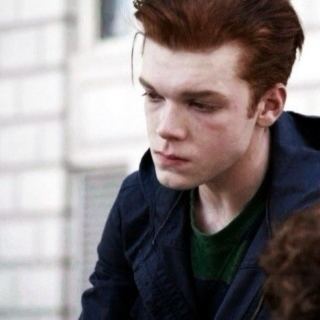 Ian Gallagher wearing a dark blue jacket and green t-shirt