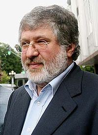 Ihor Kolomoyskyi looking serious with gray hair, a beard and mustache and wearing a white shirt under a black coat