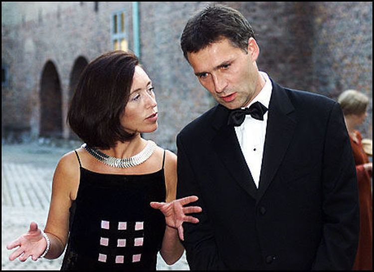 Ingrid Schulerud and Jens Stoltenberg are talking with each other while Ingrid moving her hands. Ingrid with shoulder-length hair, wearing a silver necklace, and a black spaghetti dress while Jens is wearing a black coat over white long sleeves and a black bowtie.
