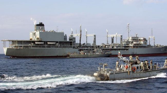 The Iranian ship Kharg, a modified Ol-class fleet replenishment oiler of the Islamic Republic of Iran Navy sailing in the ocean surrounded by two boats where the Iranian Navy on board.