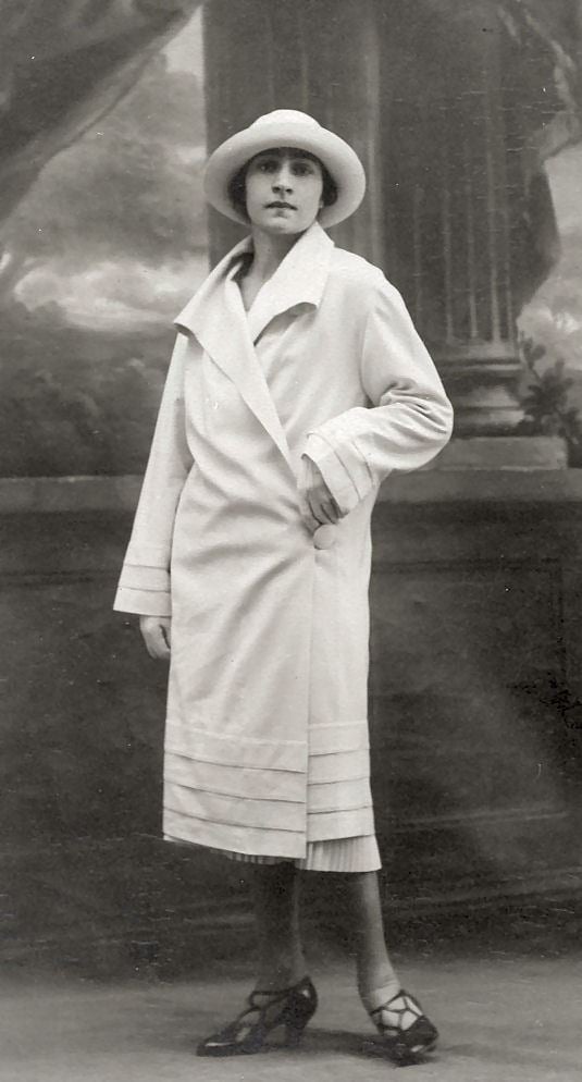 Irena Krzywicka standing and looking fierce while wearing a white coat, a white hat, and black heels