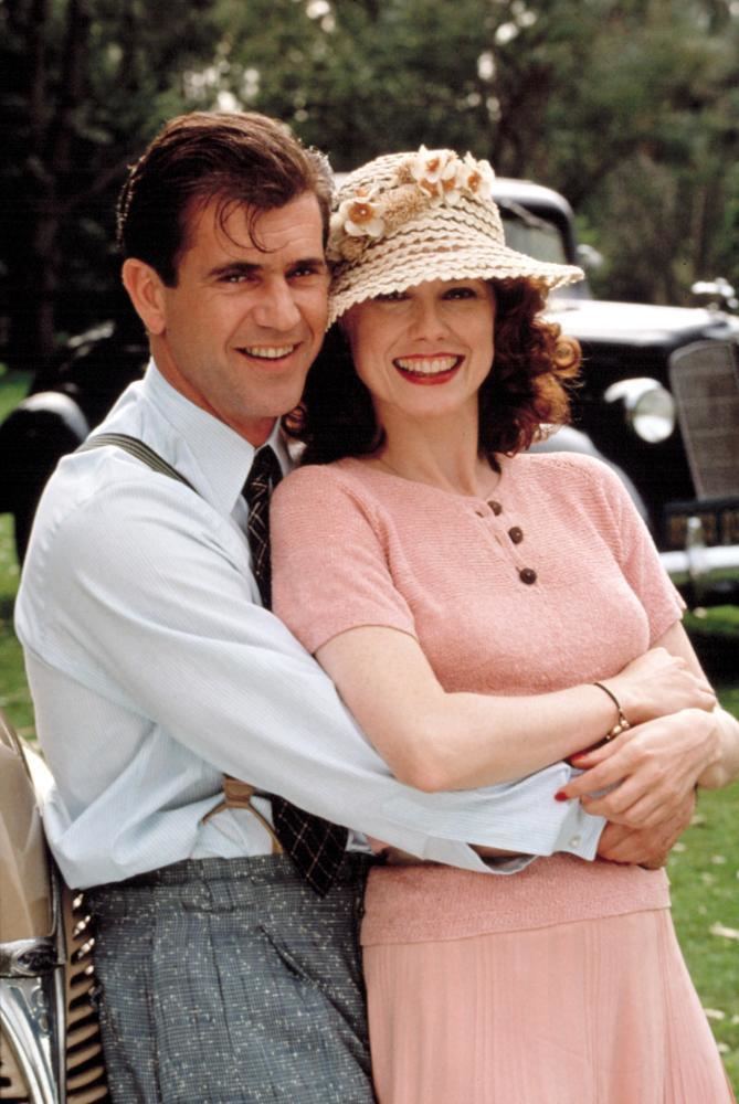 Isabel Glasser wearing a pink dress and floral hat and Mel Gibson wearing a white long sleeves