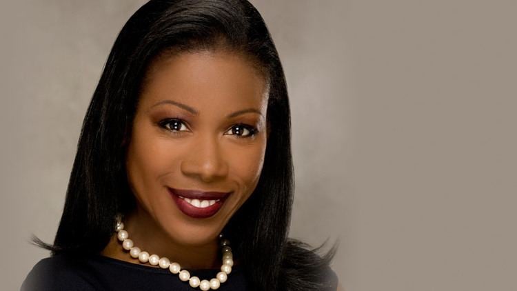 Isabel Wilkerson smiling while wearing a black blouse and pearl necklace
