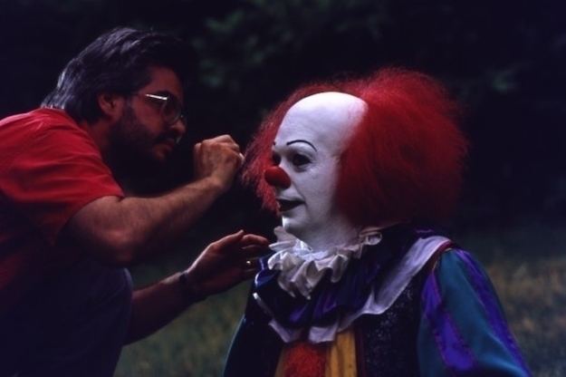 A man fixing the hair of Tim Curry who portrayed the role of Pennywise in the 1990 psychological horror drama miniseries, It