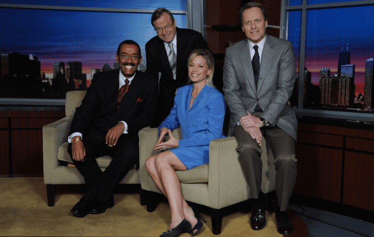 Robert Jordan, Jim Ramsey, Jackie Bange, and Rich King are smiling and sitting on the couch while Jackie is wearing a blue coat and skirt