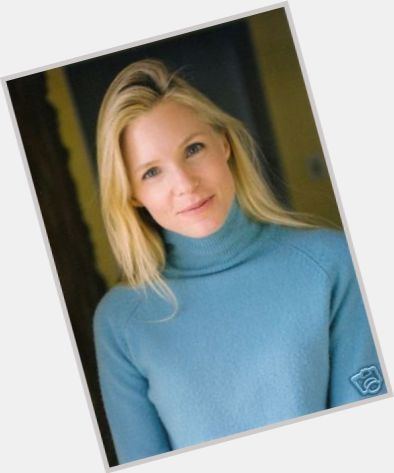 Jackie Swanson smiling while wearing a blue turtle-neck long sleeve.